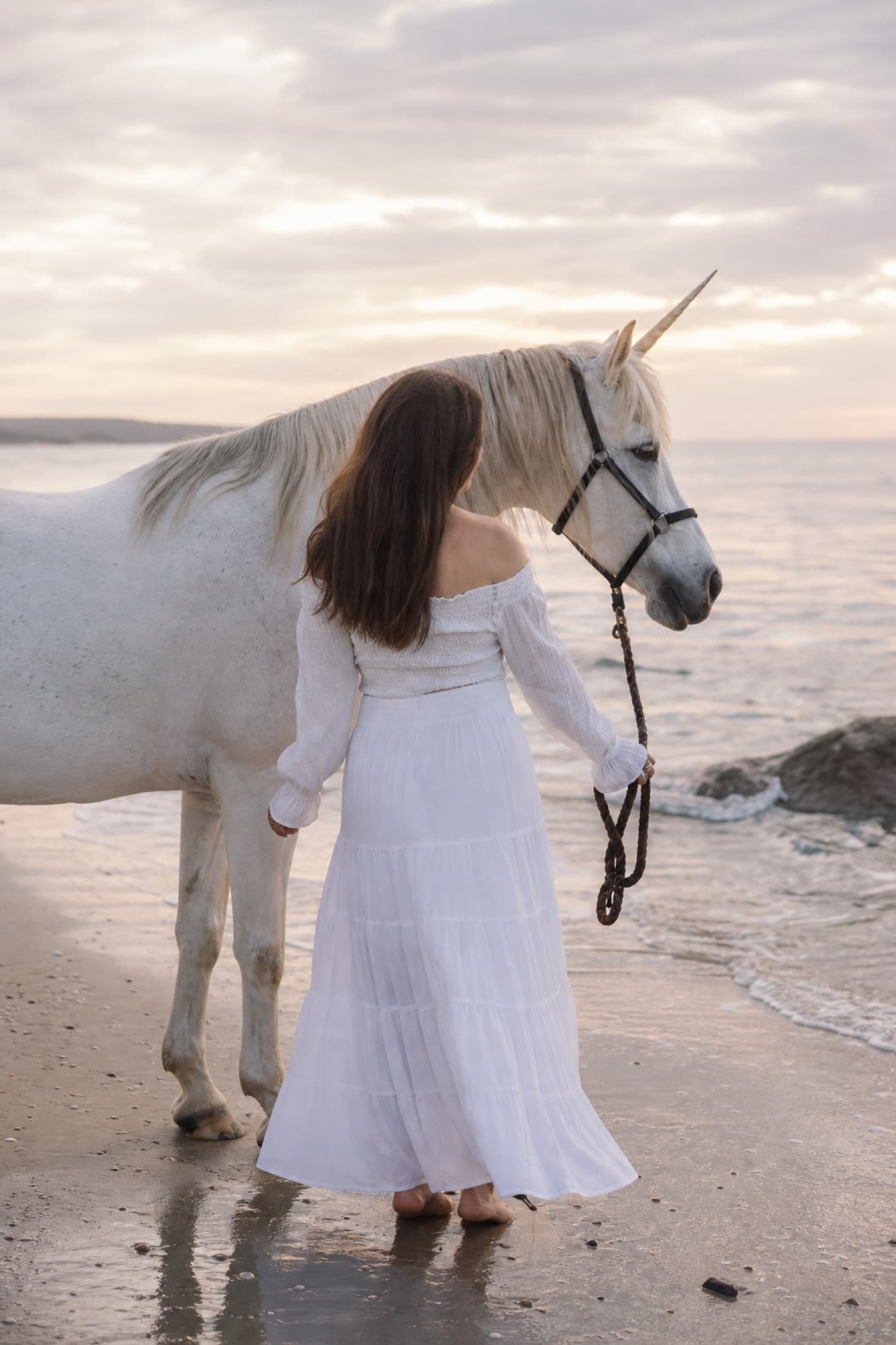 Stille foto van een vrouw met unicorn op het strand